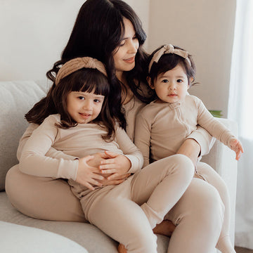 A woman holding two children wearing matching outfits.