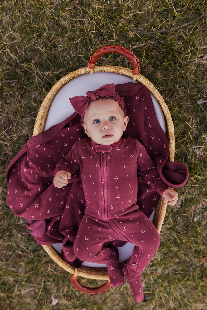 Child wearing Organic Cozy Blanket in Sugarplum Cherries.