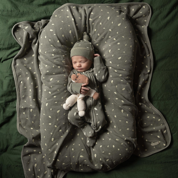 Child wearing Organic Cozy Top-Knot Hat in Hunter Leaves.