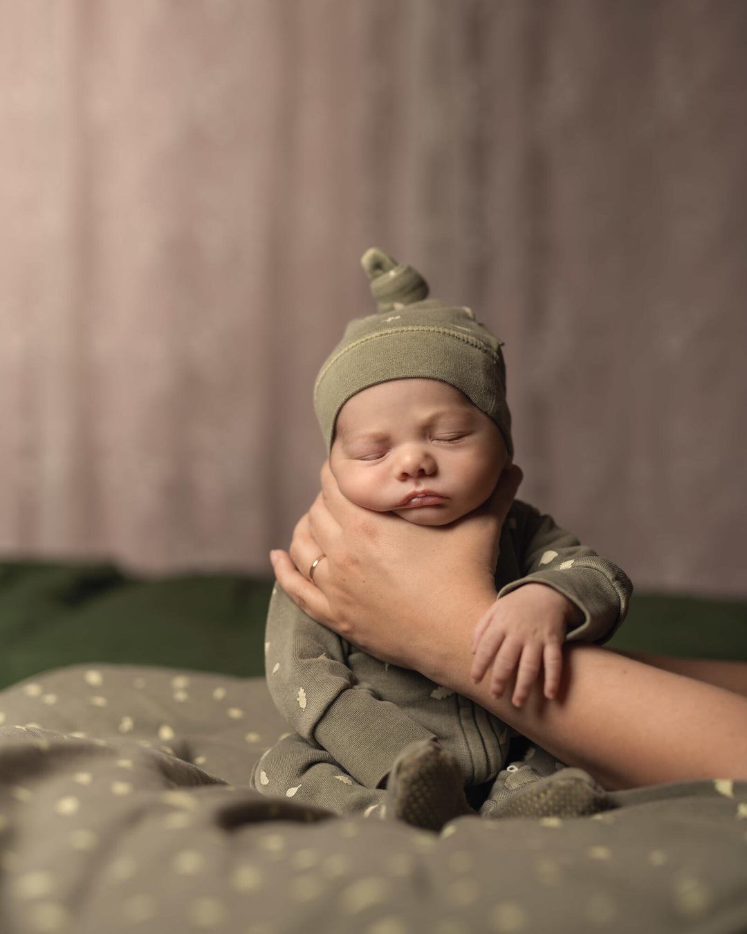 Child wearing Organic Cozy Top-Knot Hat in Hunter Leaves.