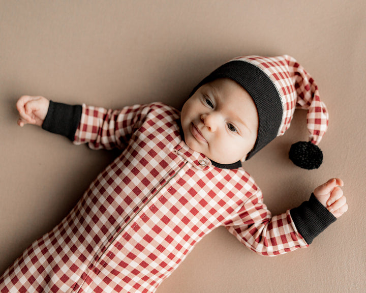 Child wearing Holiday 2-Way Zipper Footie & Cap Set in Crimson Plaid.