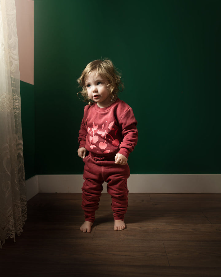 Child wearing Kids' Organic Cozy Graphic Sweatshirt & Jogger Set in Sugarplum Cherries.