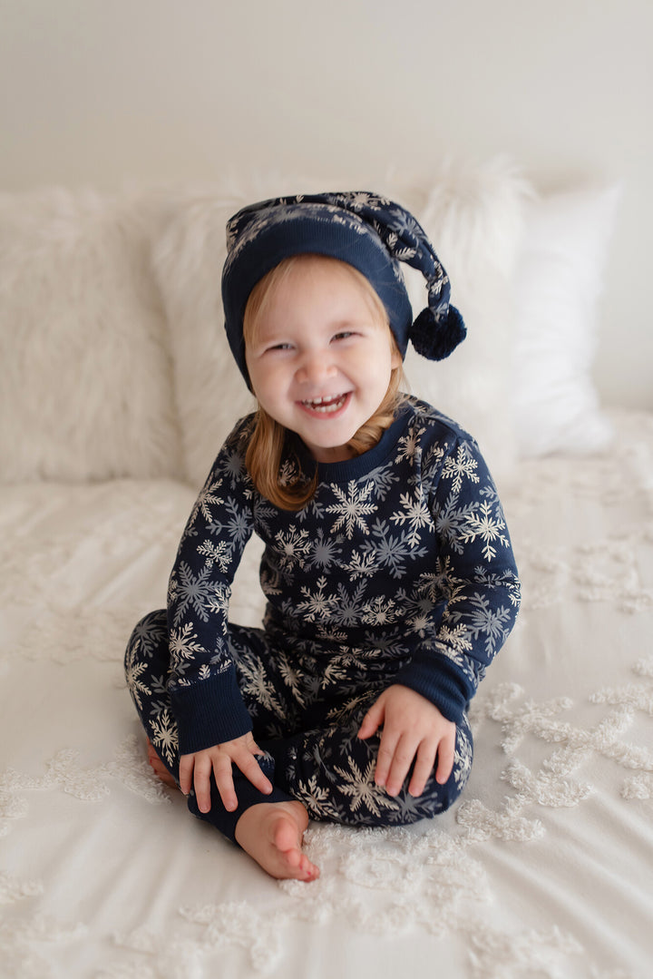 Child wearing Kids' Organic Holiday PJ & Cap Set in Snowflakes.