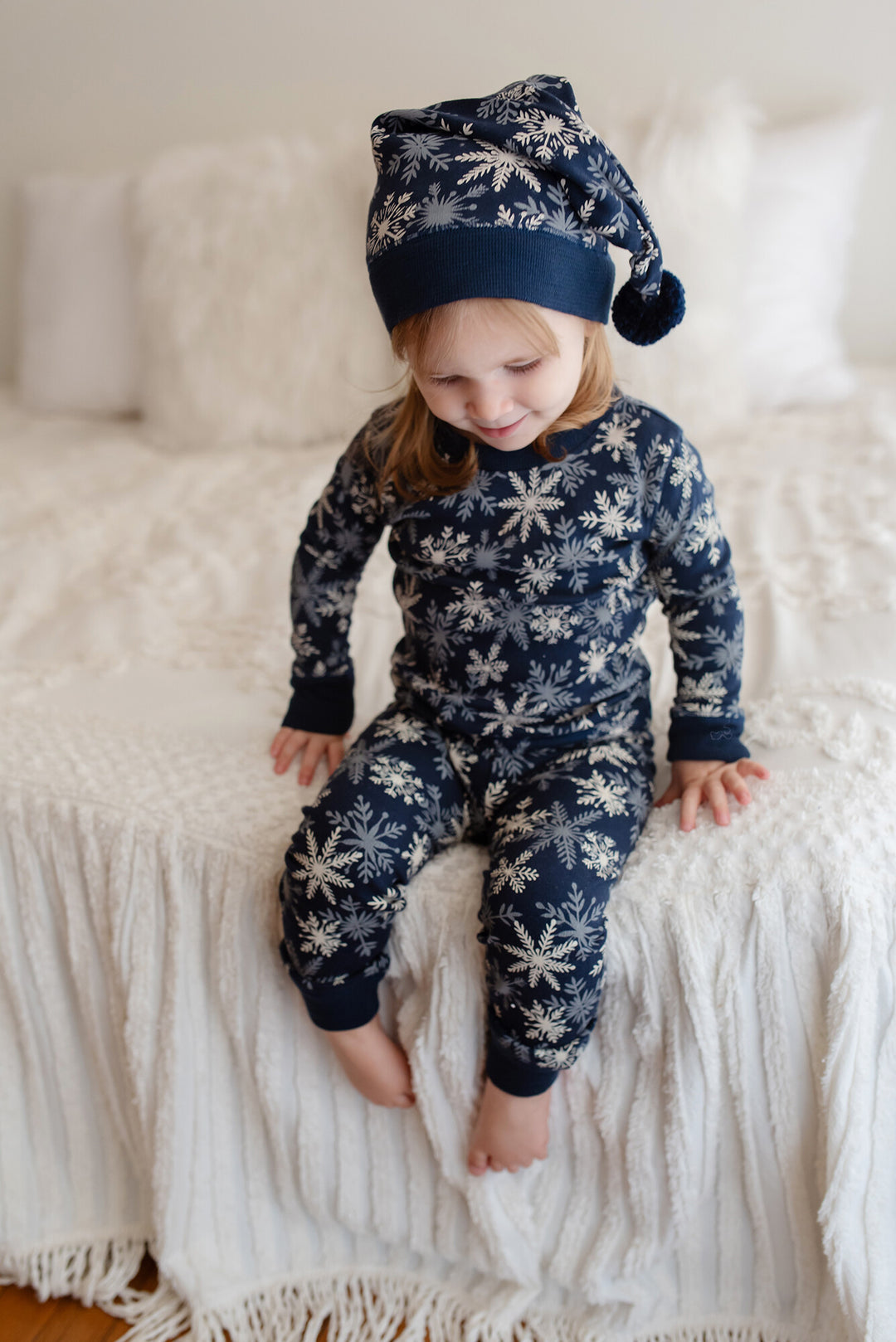 Child wearing Kids' Organic Holiday PJ & Cap Set in Snowflakes.