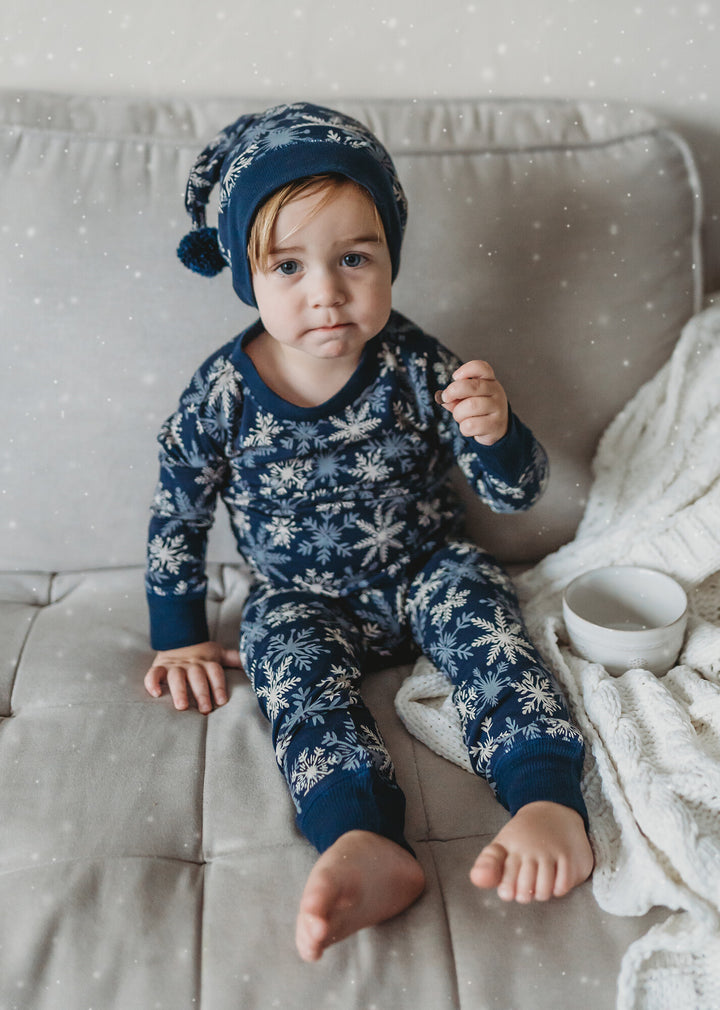 Child wearing Kids' Organic Holiday PJ & Cap Set in Snowflakes.