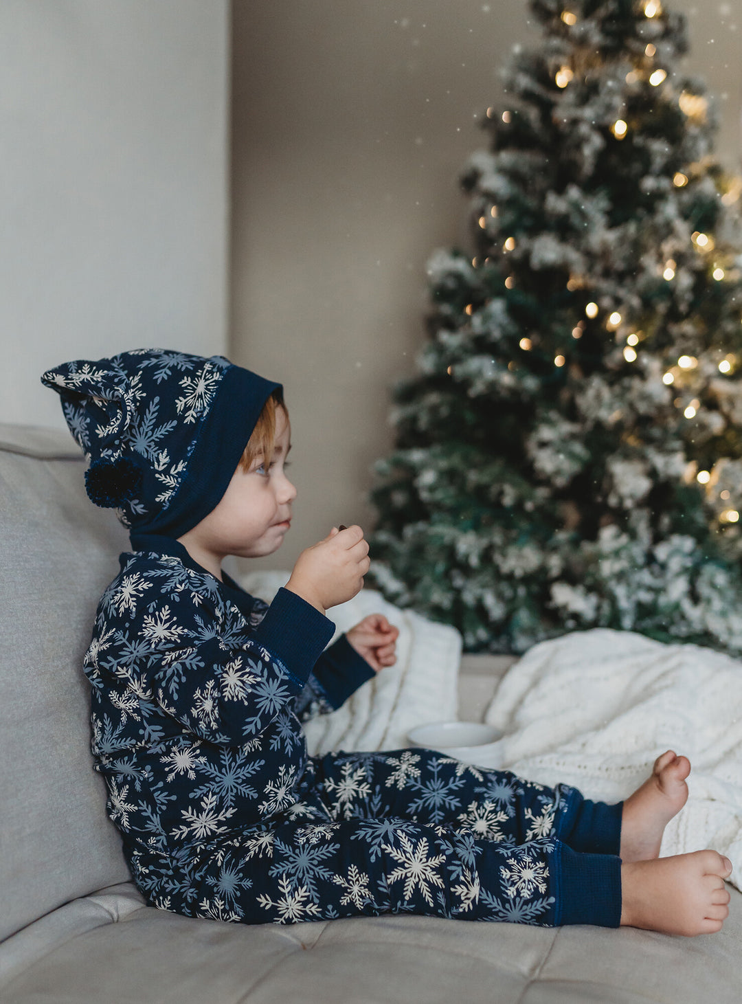 Child wearing Kids' Organic Holiday PJ & Cap Set in Snowflakes.