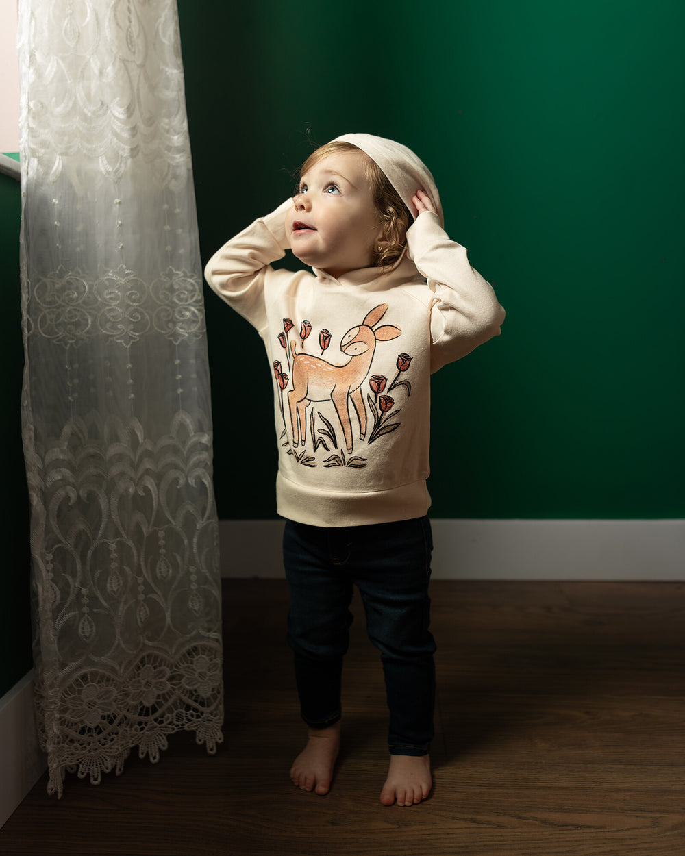 Child wearing Kids' Organic Printed Raglan Hoodie in Doe-a-Deer Graphic.