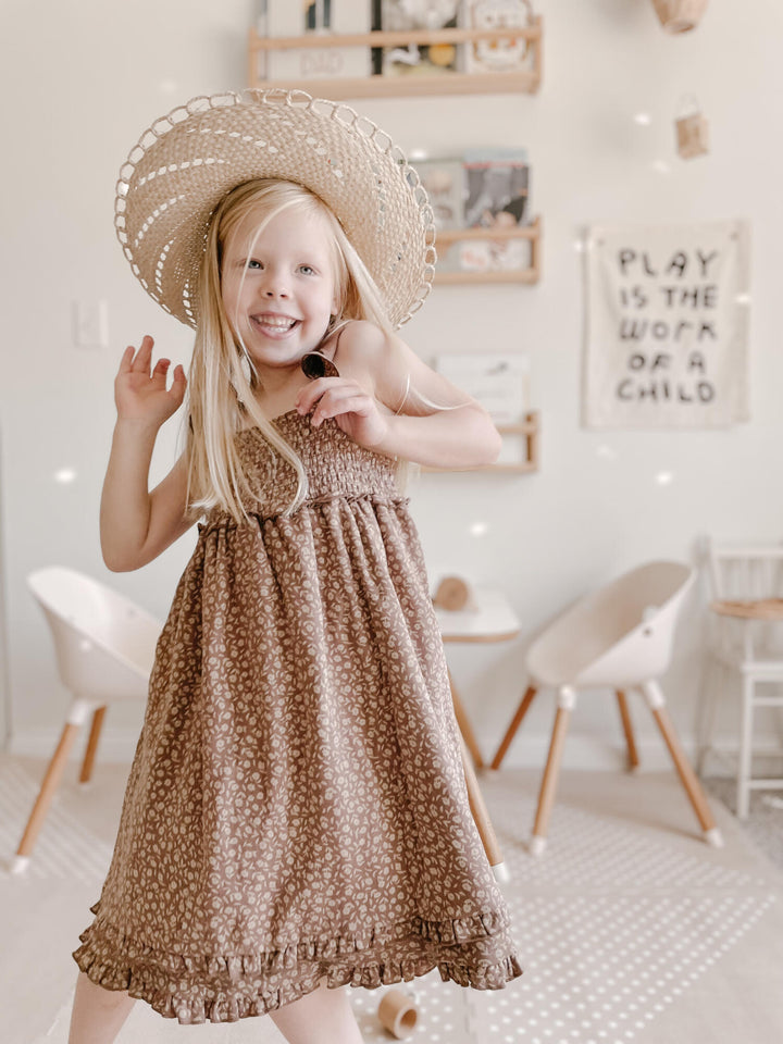 Child wearing Kids' Organic Printed Smocked Summer Dress in Latte Floral.