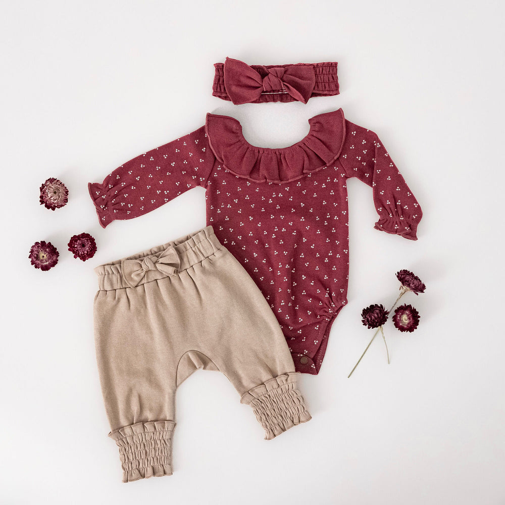 Child wearing Organic Ruffle Neck Bodysuit in Appleberry Dots.