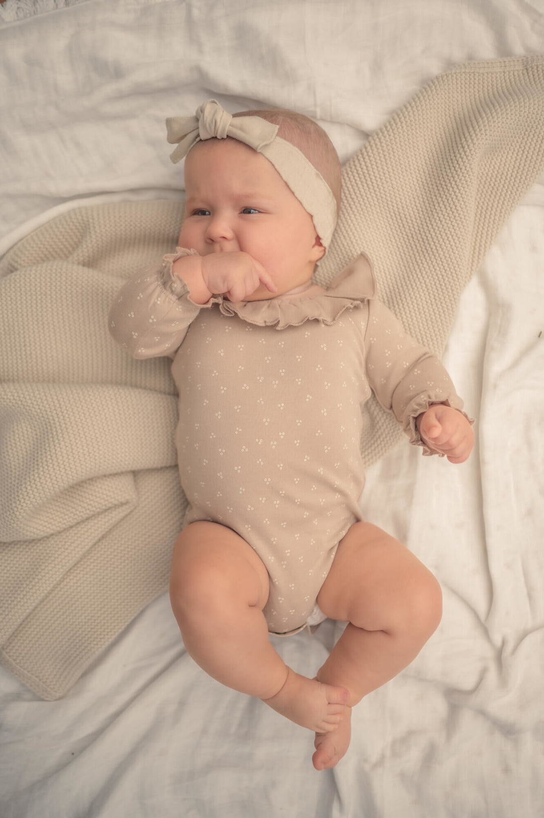 Child wearing Organic Ruffle Neck Bodysuit in Oatmeal Dots.