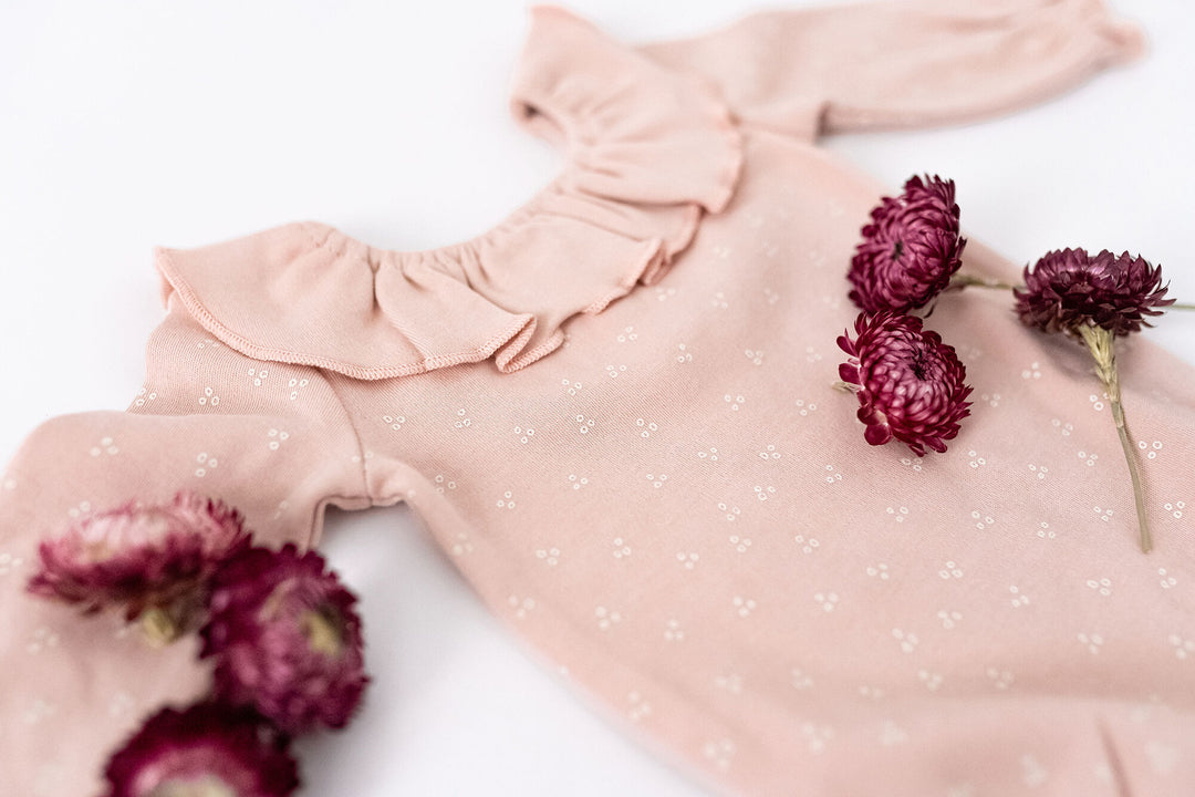 Child wearing Organic Ruffle Neck Bodysuit in Rosewater Dots.