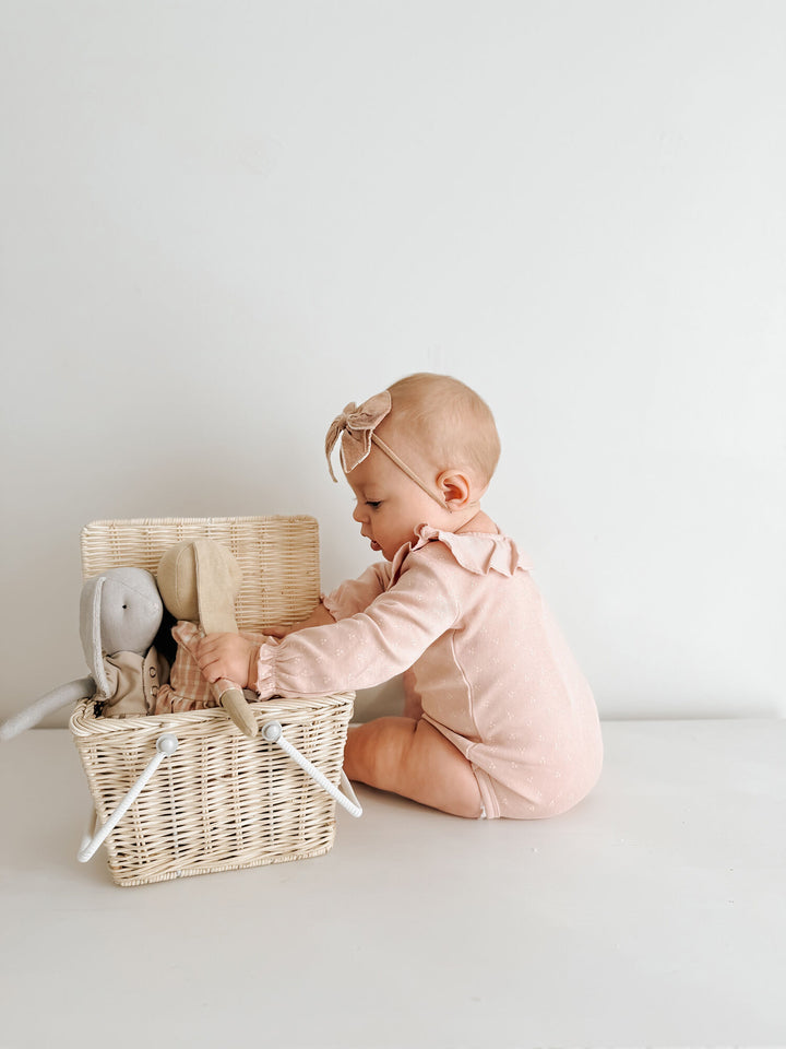 Child wearing Organic Ruffle Neck Bodysuit in Rosewater Dots.