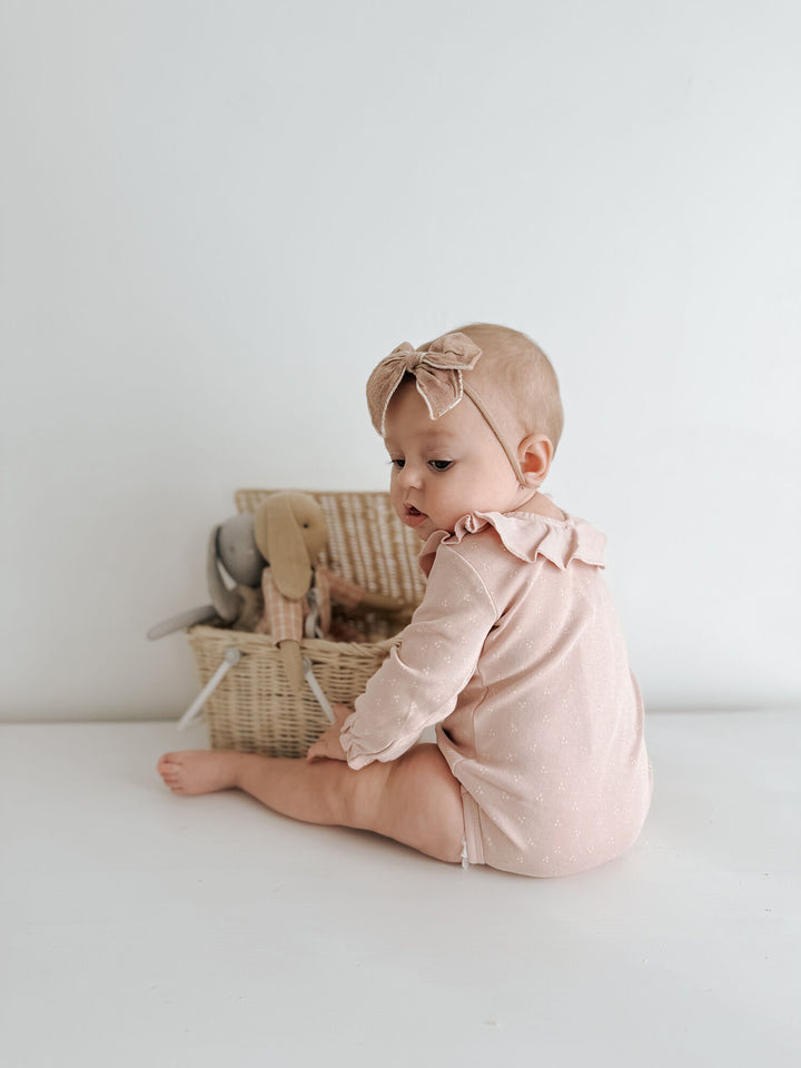 Child wearing Organic Ruffle Neck Bodysuit in Rosewater Dots.