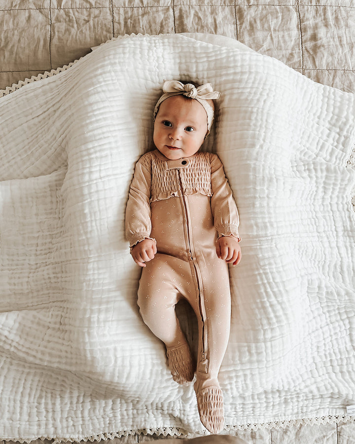 Child wearing Organic Smocked Zipper Footie in Oatmeal Dots.