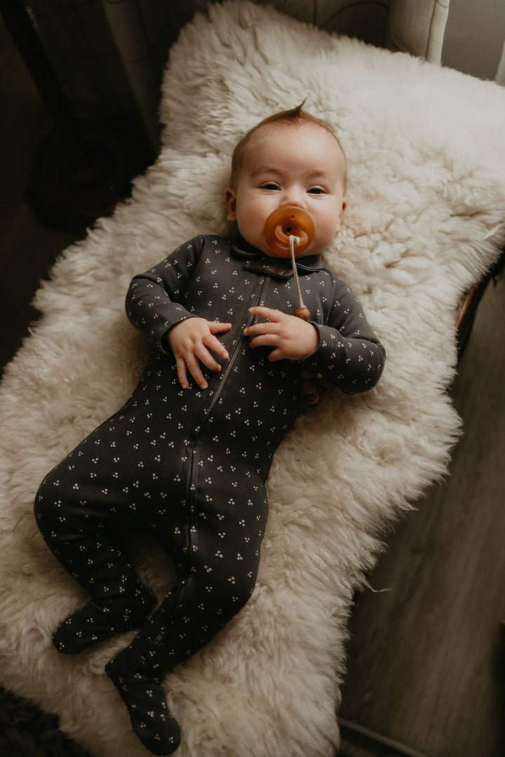 Child wearing Organic Polo Zipper Footie in Charcoal Dots.