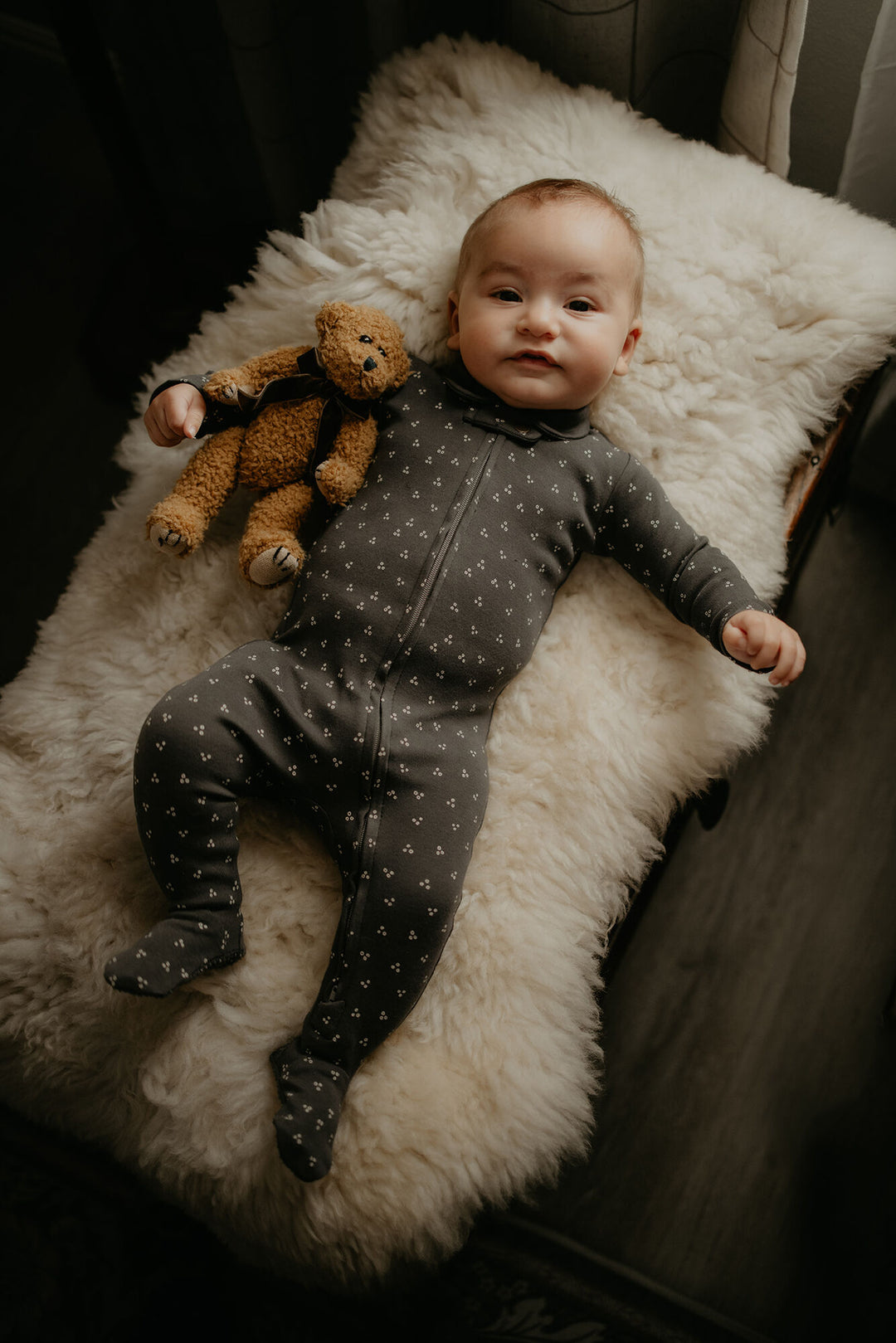 Child wearing Organic Polo Zipper Footie in Charcoal Dots.