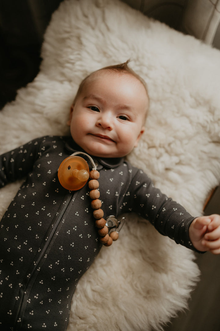 Child wearing Organic Polo Zipper Footie in Charcoal Dots.