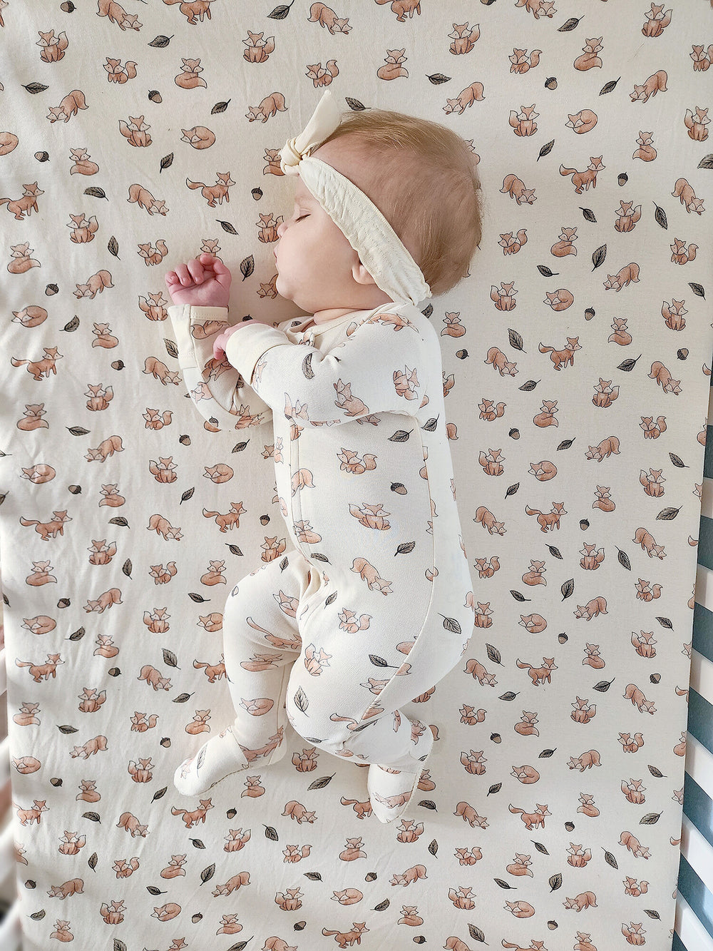 Child wearing Organic Crib Sheets in Foxy.