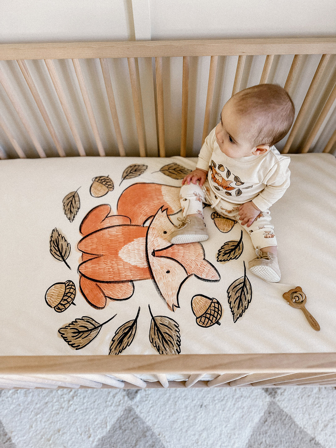 Child wearing Organic Crib Sheets in Foxy Graphic.