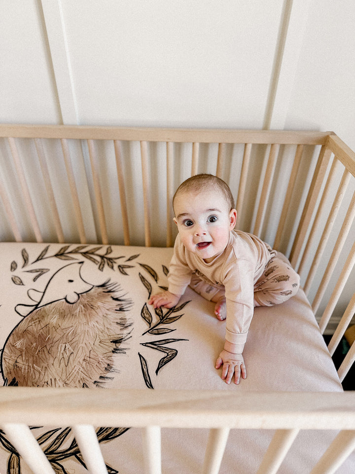 Child wearing Organic Crib Sheets in Prickles Graphic.