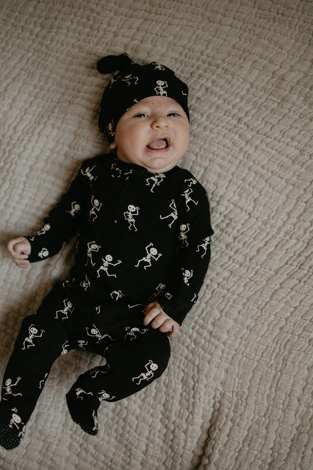 Child wearing Organic Banded Top-Knot Hat in Dancing Skeletons.