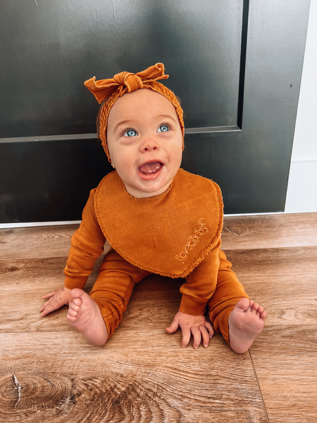 Child wearing French Terry Reversible Bib in Butterscotch.