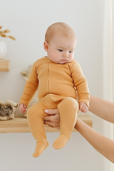 Child wearing Organic Zipper Footie in Honey.