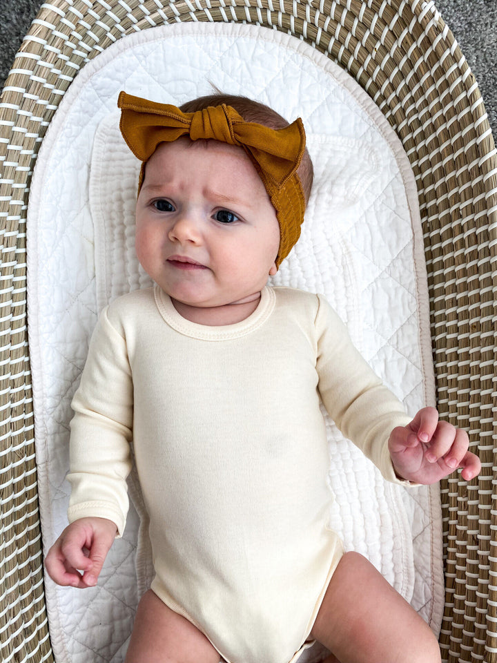 Child wearing Organic Smocked Tie Headband in Butterscotch.