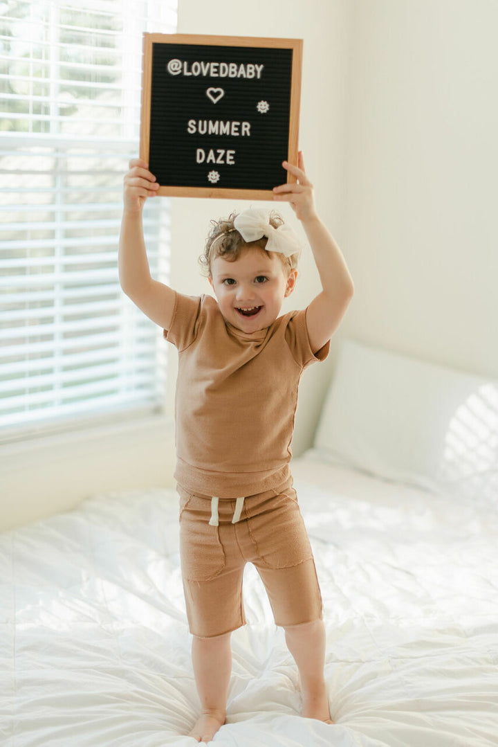 Child wearing Kids' French Terry Shorts & Tee Set in Adobe.